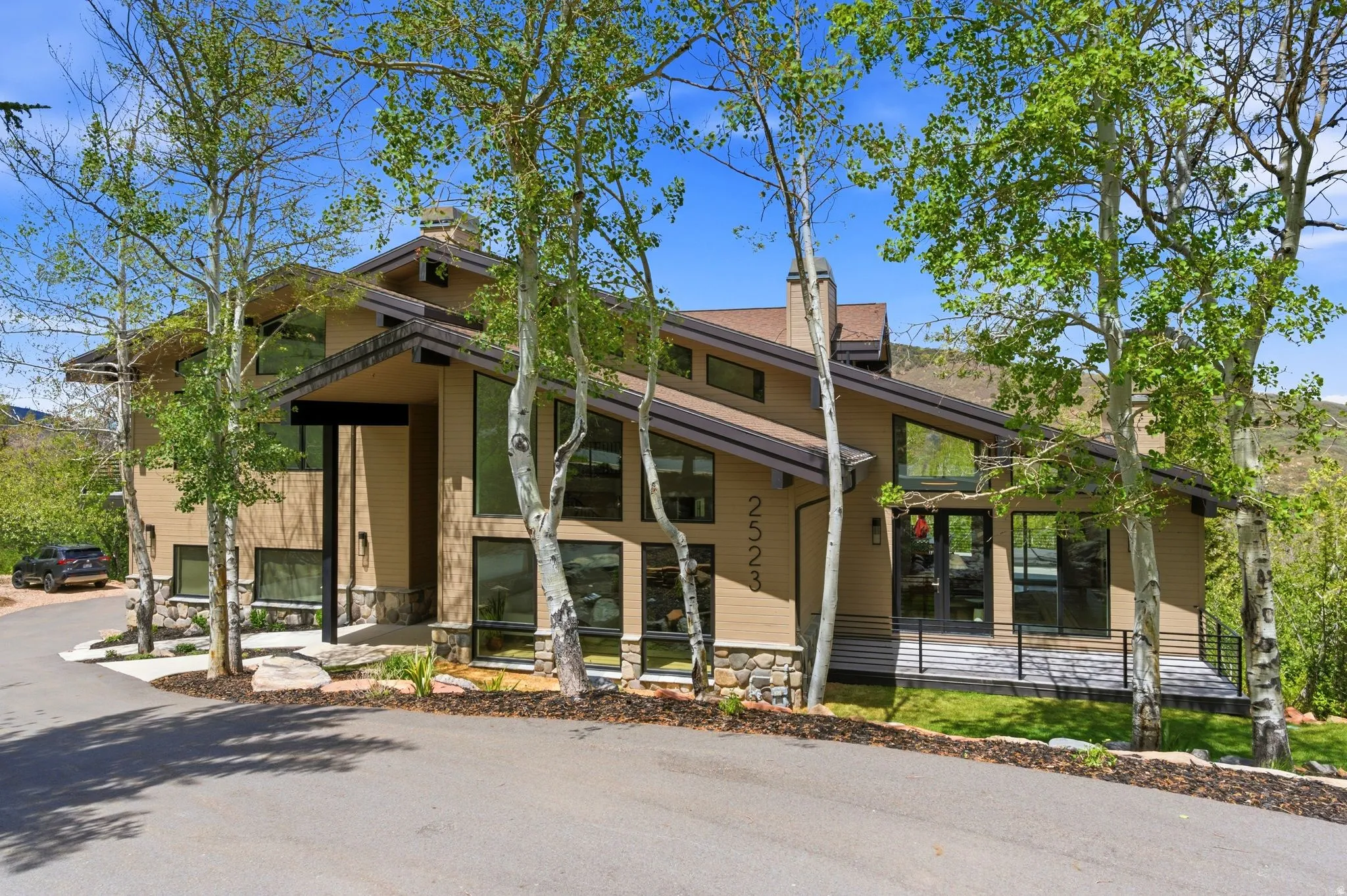Modern architectural residence featuring multiple large windows, stone accents, and a sloped roofline