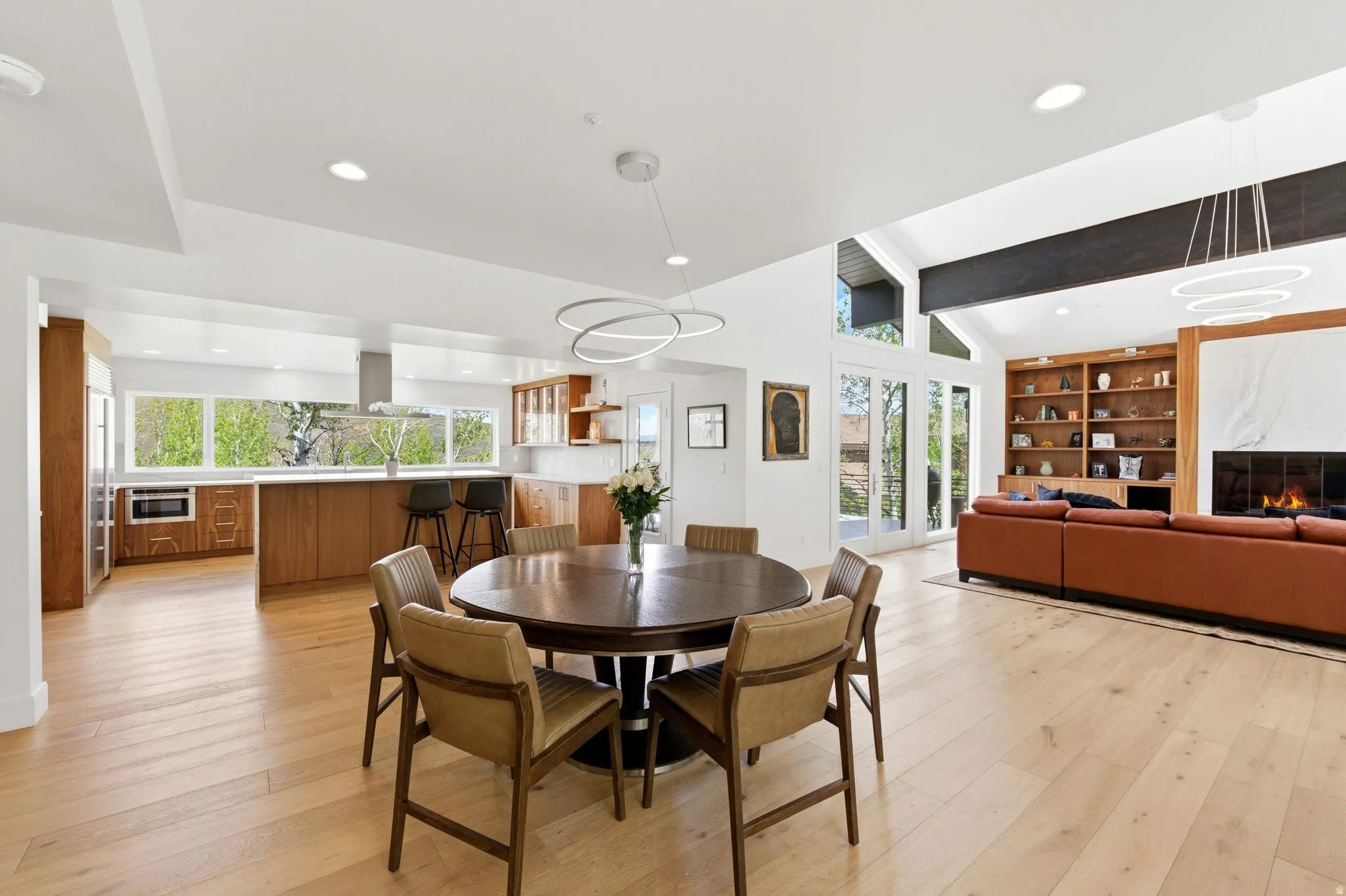 Open-concept living space featuring wood-finish flooring, recessed lighting, and a vaulted ceiling with exposed beams