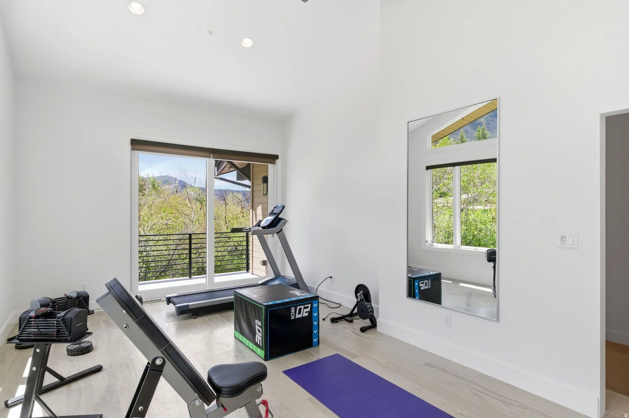 Spacious room with wood-finish flooring, recessed lighting, and a full-length wall mirror