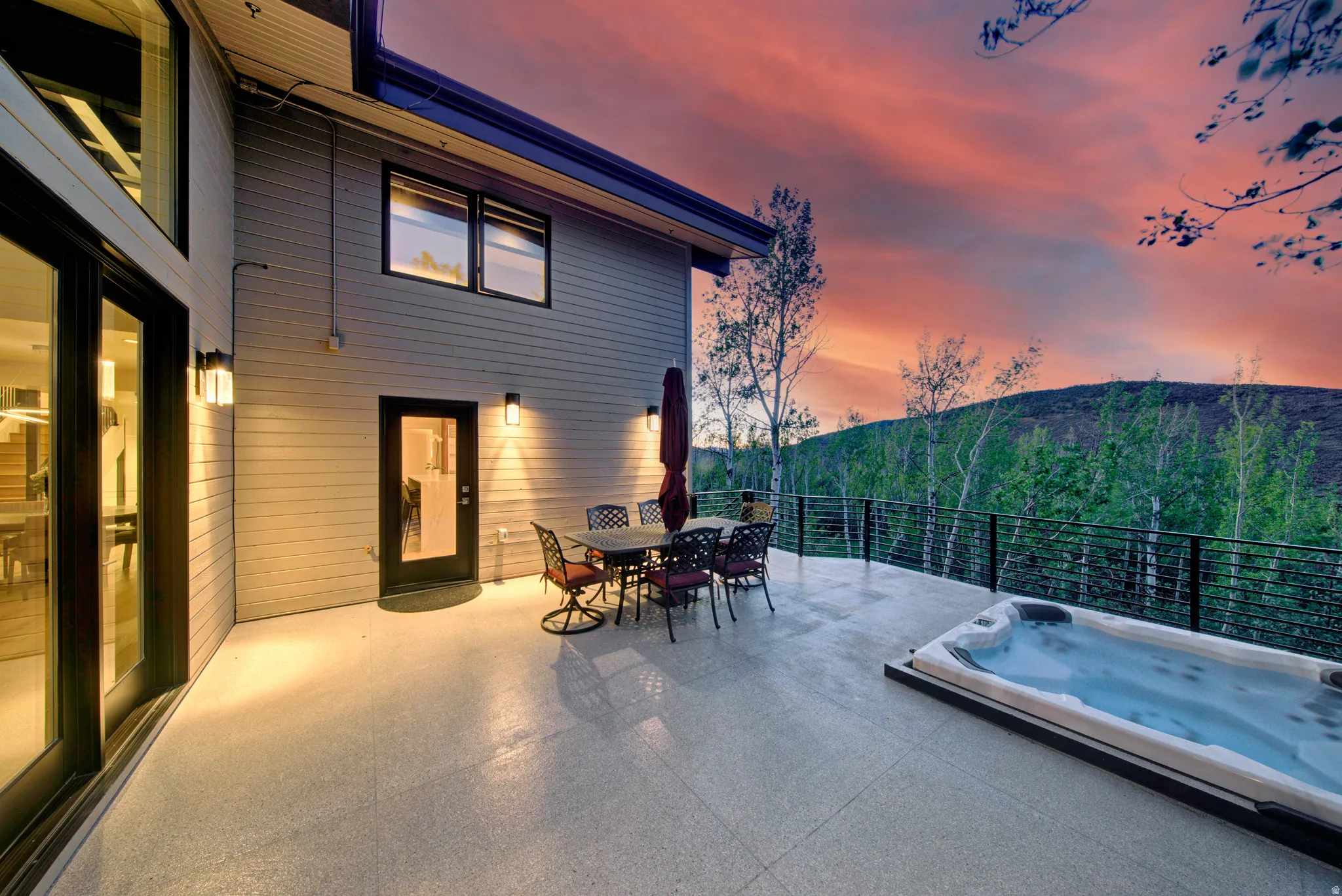 Expansive outdoor patio featuring an integrated hot tub, contemporary metal railing, and direct landscape scenery
