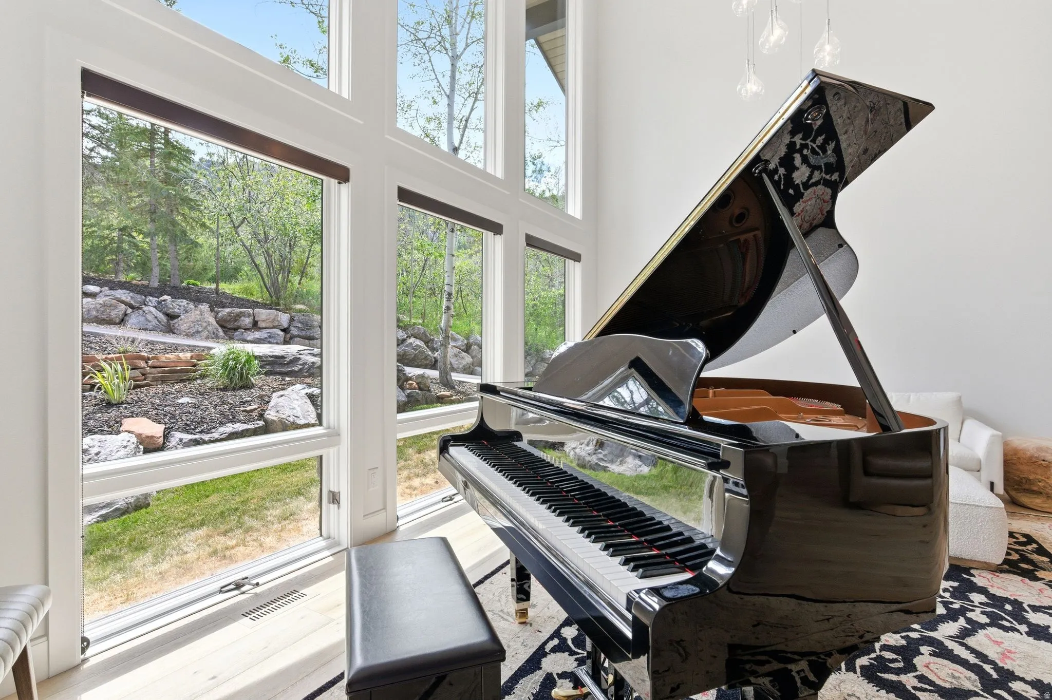 Two-story window wall showcasing a landscaped rock garden and mature trees