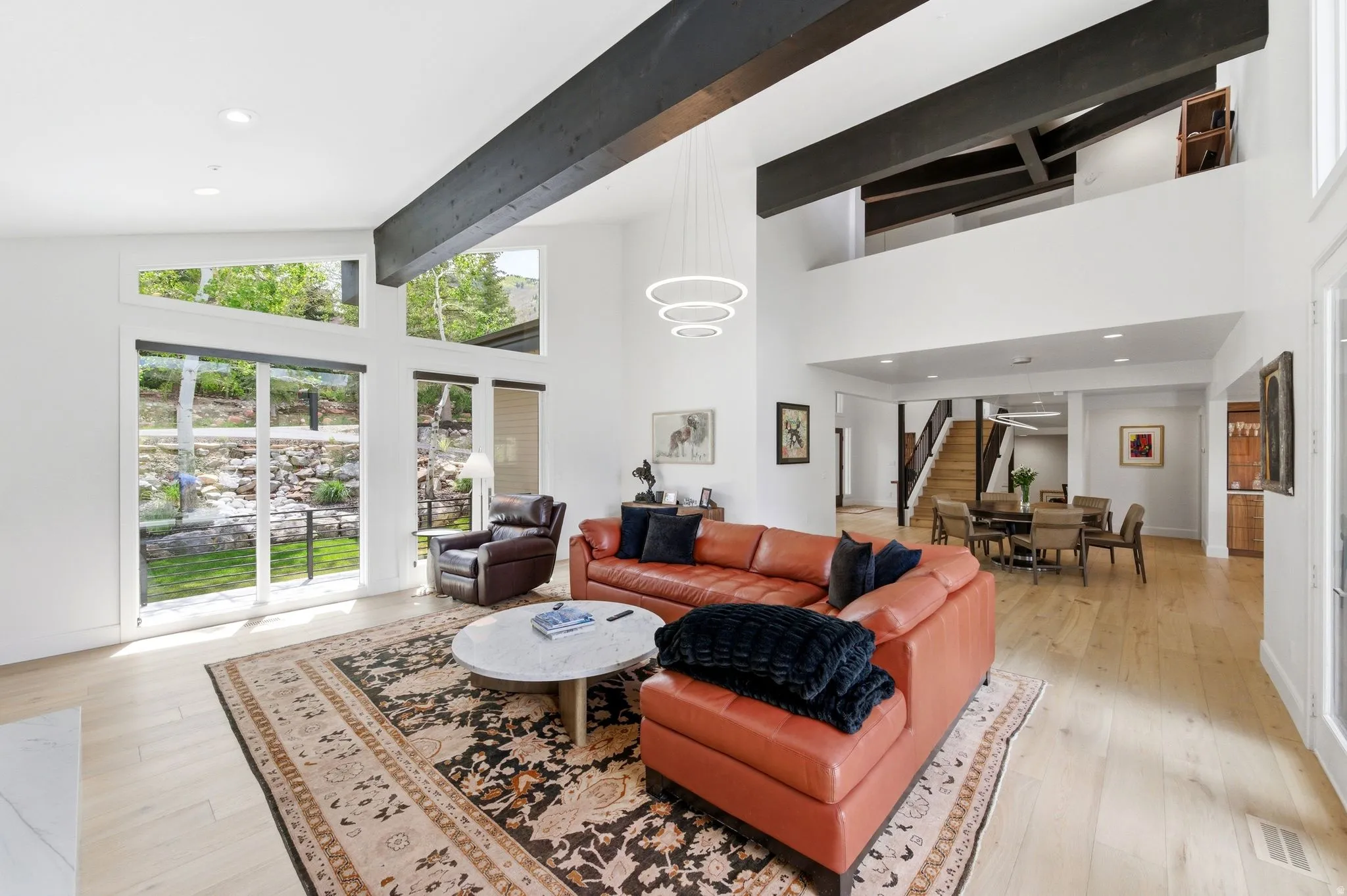 Vaulted living space featuring exposed wood beams and a contemporary chandelier