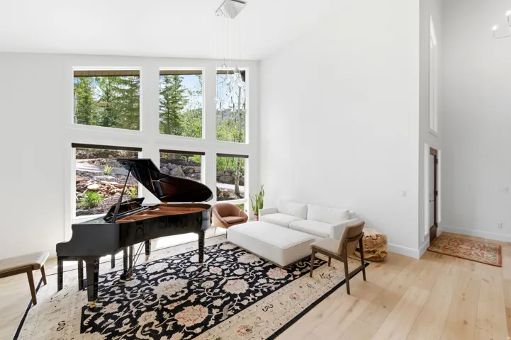 Spacious room with high ceilings, light wood-finish flooring, and expansive windows