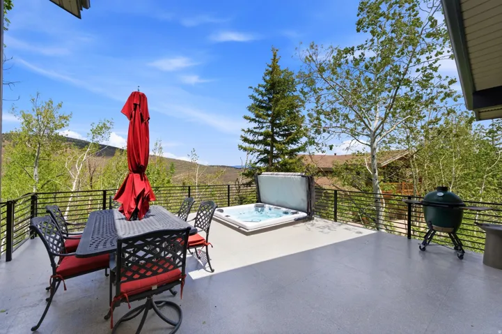 Spacious outdoor deck featuring a hot tub, mountain scenery, and horizontal metal railings