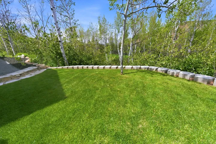 Manicured lawn with a curved paver retaining wall and natural stone steps