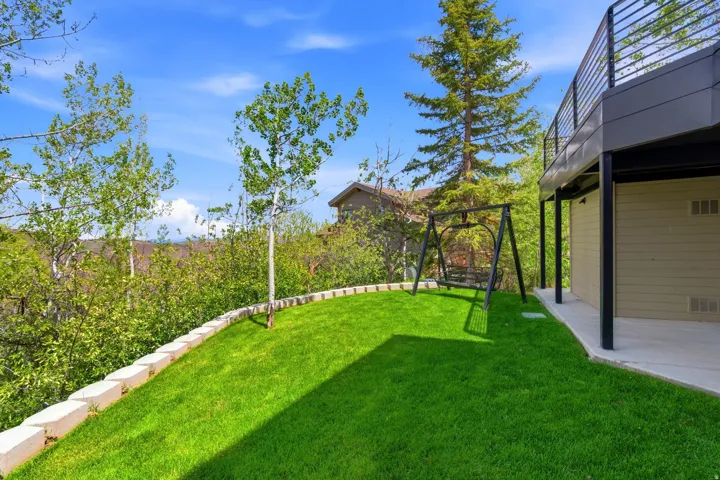 Expansive manicured lawn bordered by a stone retaining wall and mature trees