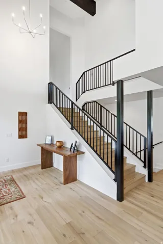 Two-story foyer featuring a contemporary chandelier, open-tread staircase with black metal railings, and wood-finish flooring