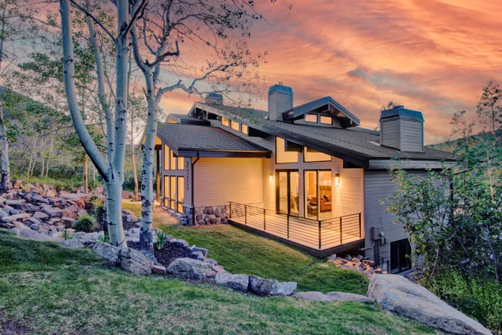 Modern mountain-style residence featuring a sloped dark roof and multiple chimneys
