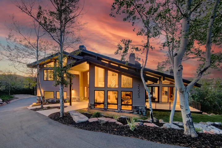 Contemporary architectural design featuring extensive window walls, a multi-pitch roofline, and a stone foundation