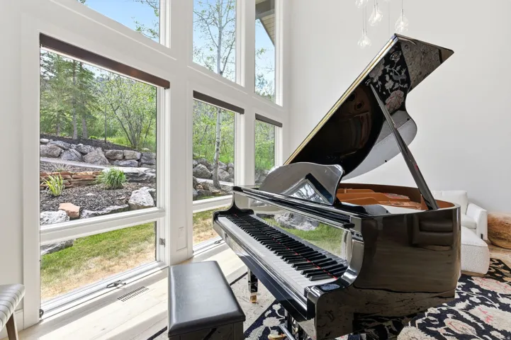 Two-story window wall showcasing a landscaped rock garden and mature trees