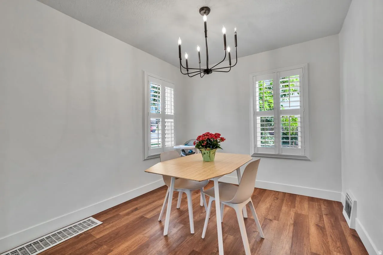 Room featuring wood-finish flooring, white walls, and a contemporary black chandelier