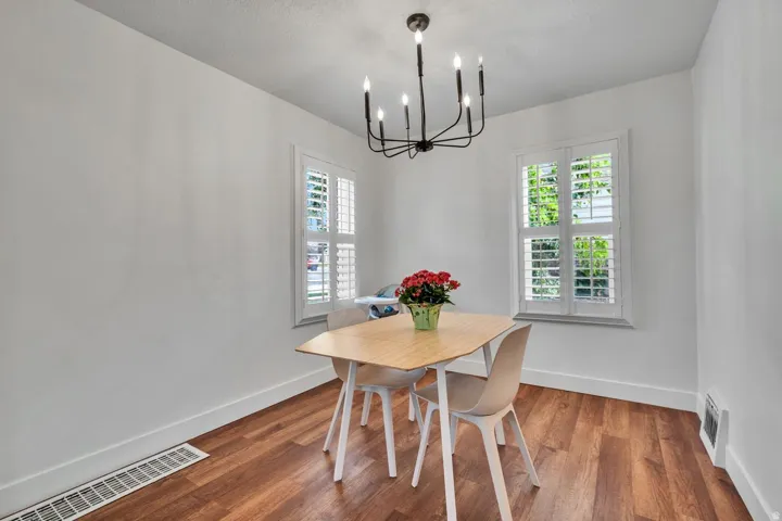Room featuring wood-finish flooring, white walls, and a contemporary black chandelier