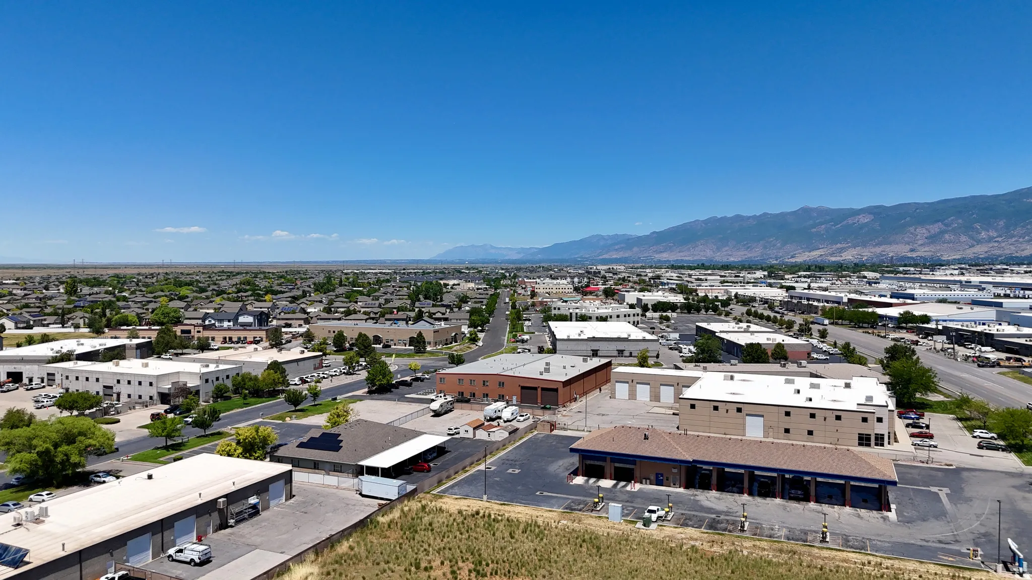 Expansive commercial property featuring a brown roofline building with multiple bays, ample paved parking, and a gravel lot