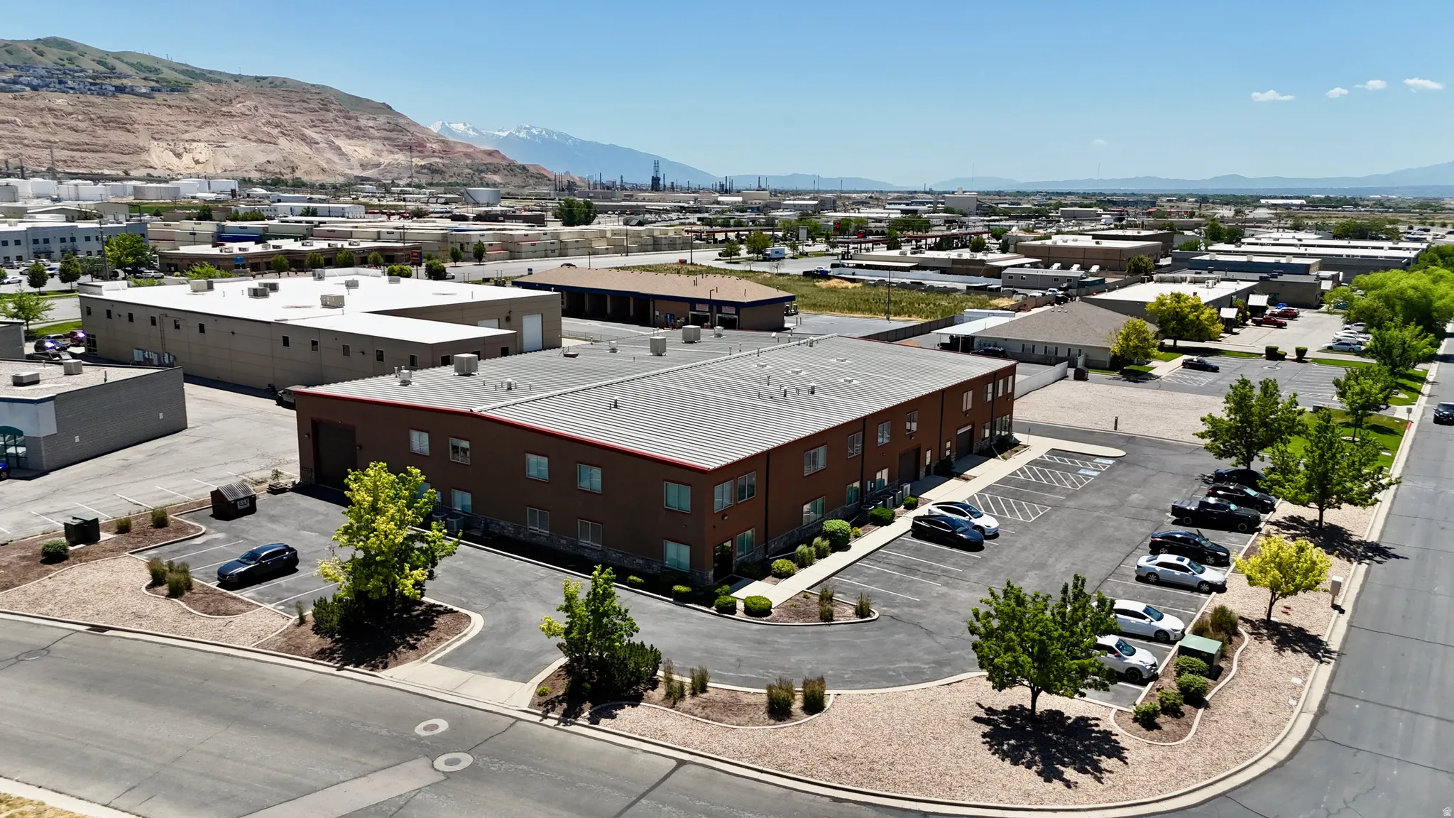 Commercial building featuring brick-colored siding and a flat roof, surrounded by paved parking areas