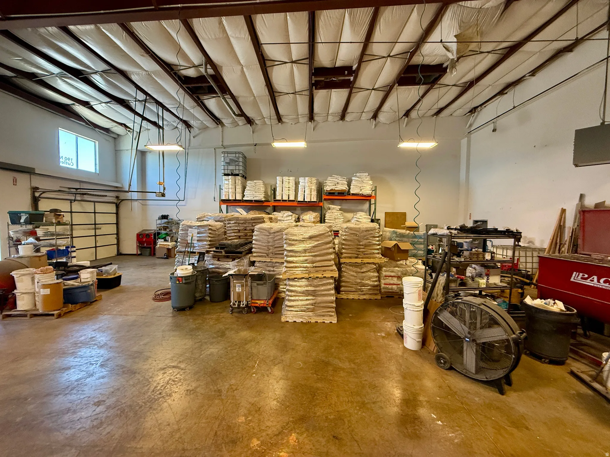 Warehouse interior featuring exposed metal ceiling trusses, insulated ceiling panels, and concrete flooring