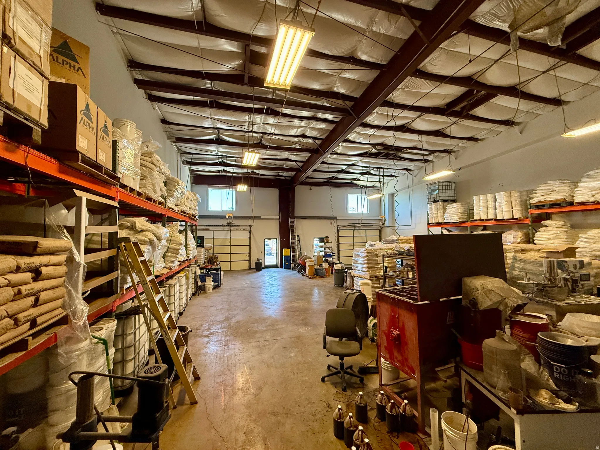 Spacious industrial interior with high ceilings featuring exposed metal beams and insulation