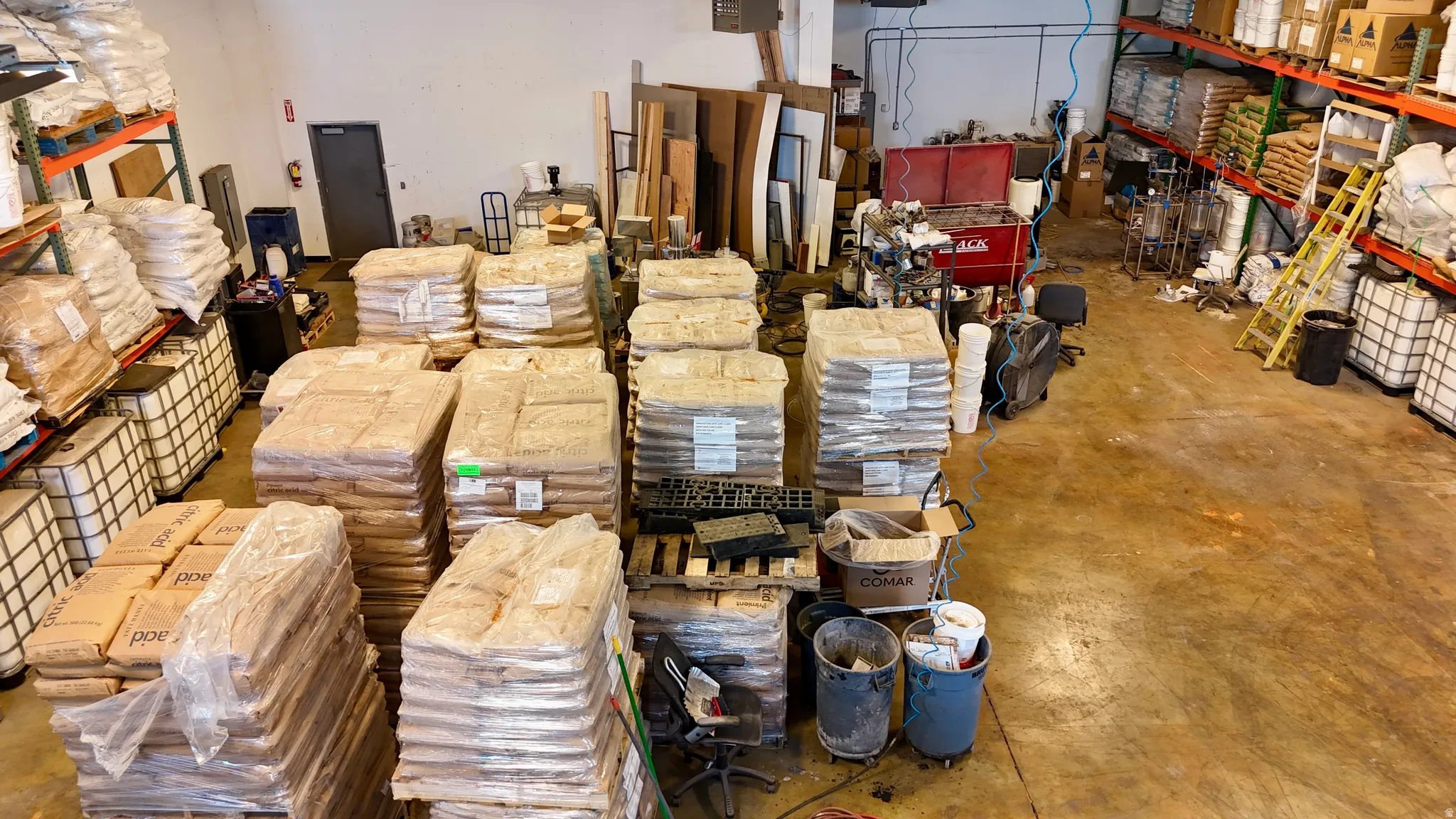 Spacious industrial warehouse interior featuring high ceilings, concrete flooring, and extensive shelving units