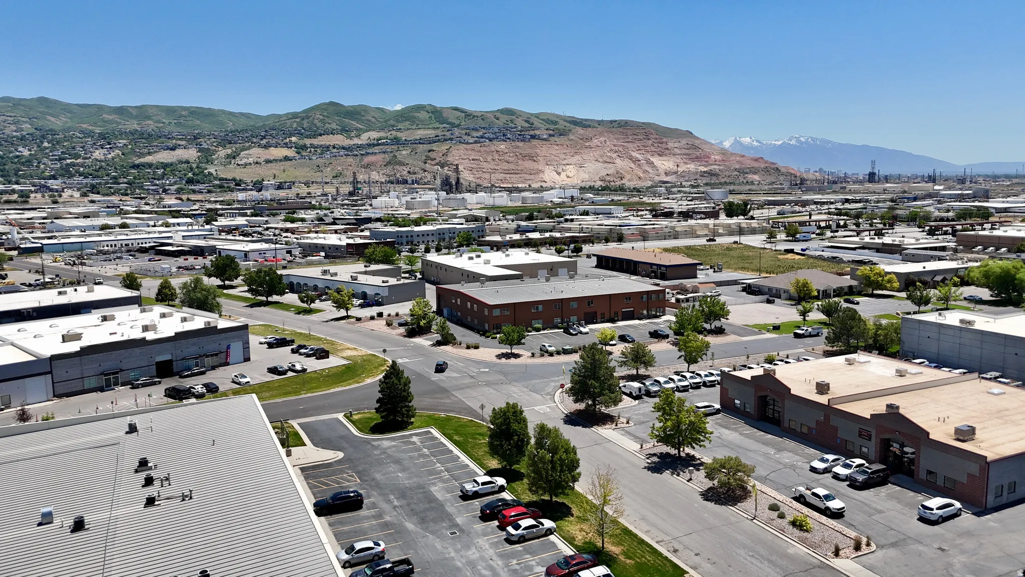 Aerial perspective showcasing a commercial district with multiple buildings, paved parking areas, and mature trees