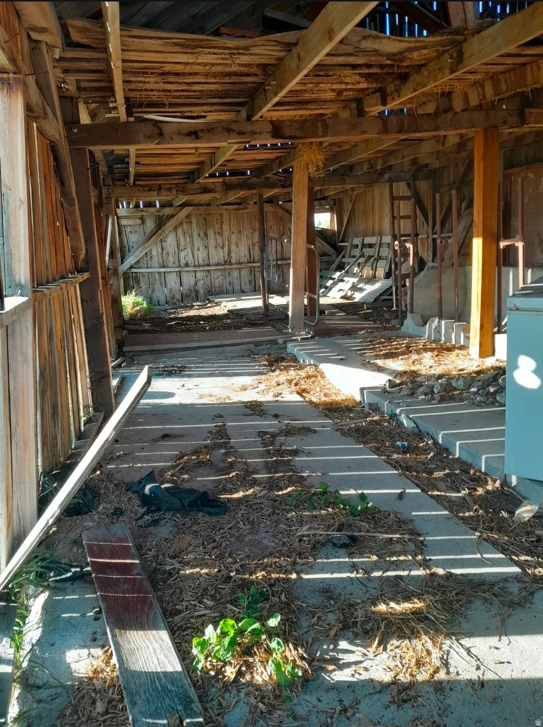 Unfinished interior space featuring exposed wood beam construction, vertical wood plank wall panels, and concrete flooring