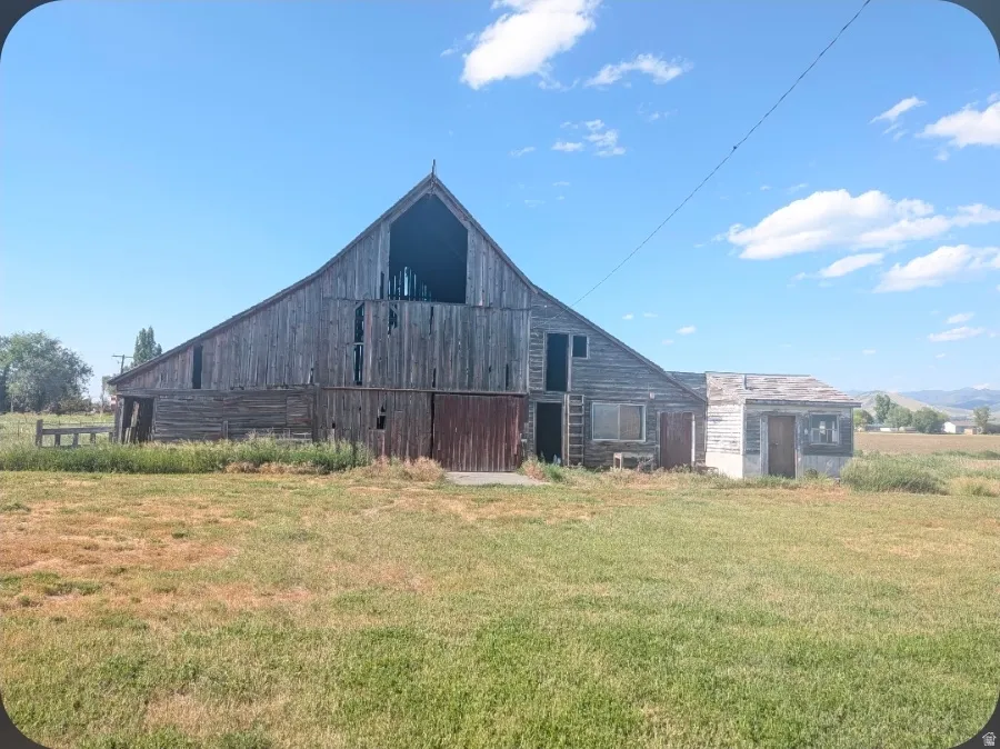 Rustic barn structure with weathered wood siding, including a peaked gable roof and a smaller attached outbuilding