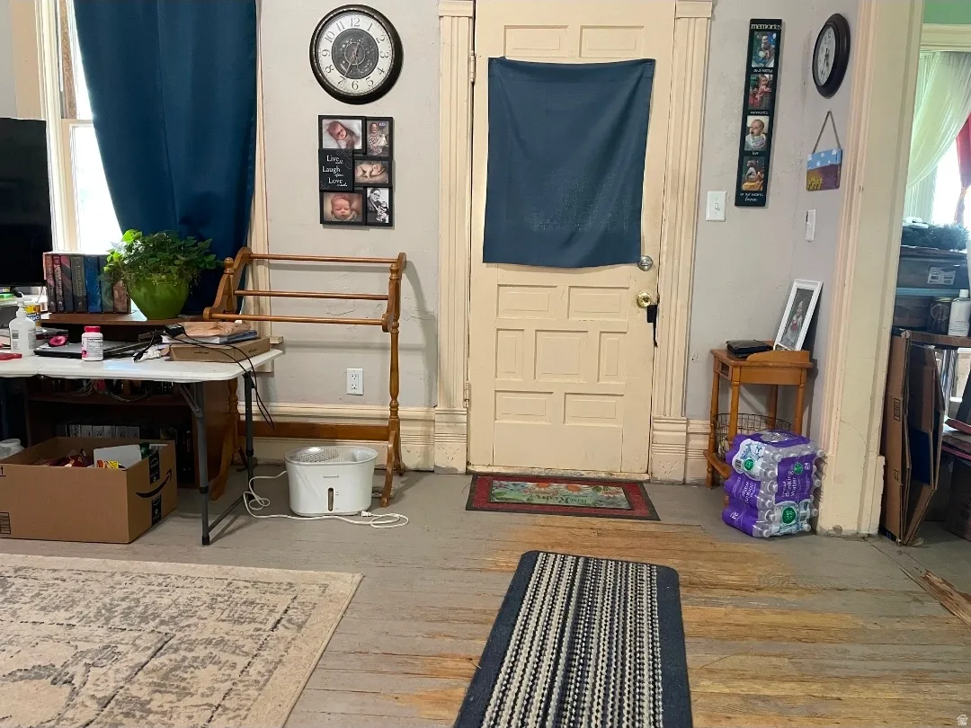 Paneled interior door with traditional trimwork, light-toned wall paint, and wood-finish flooring