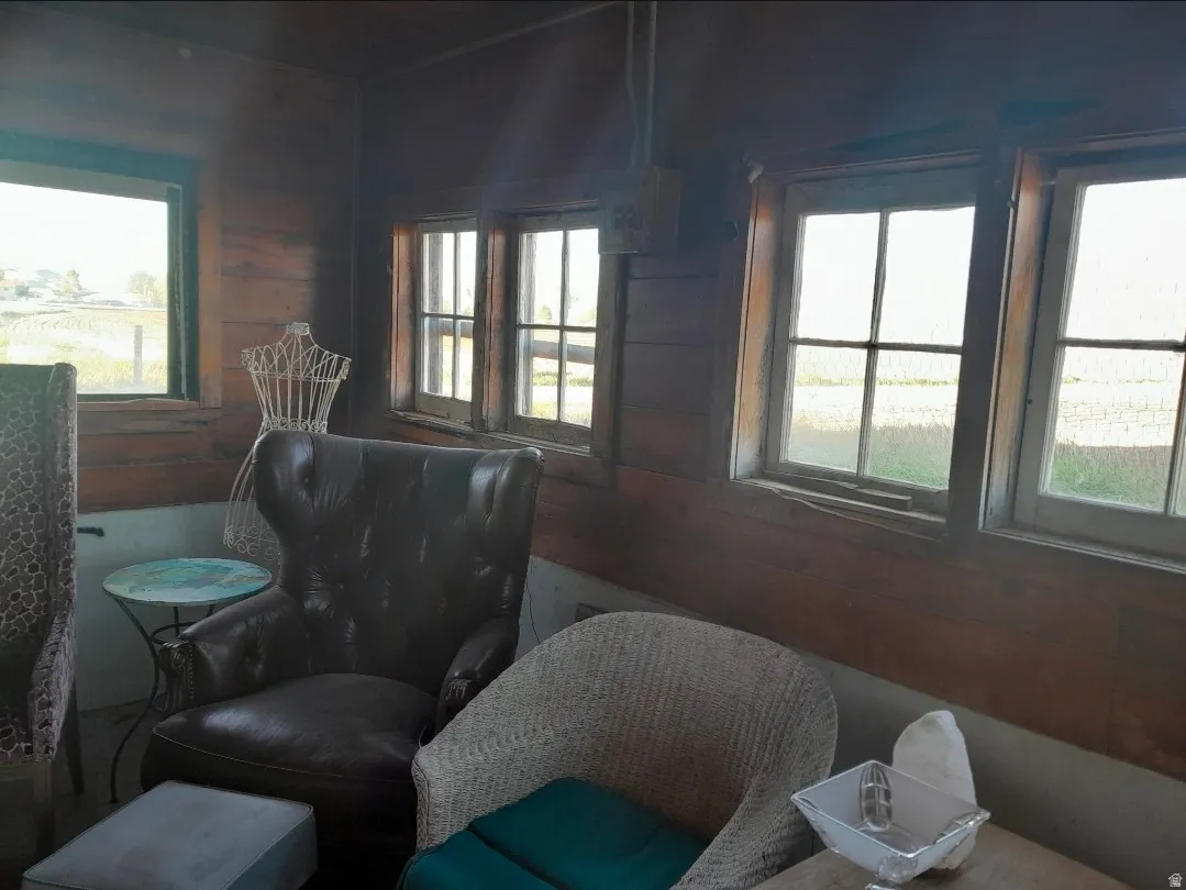 Room featuring wood-paneled walls, multiple windows providing natural light, and a visible exterior landscape