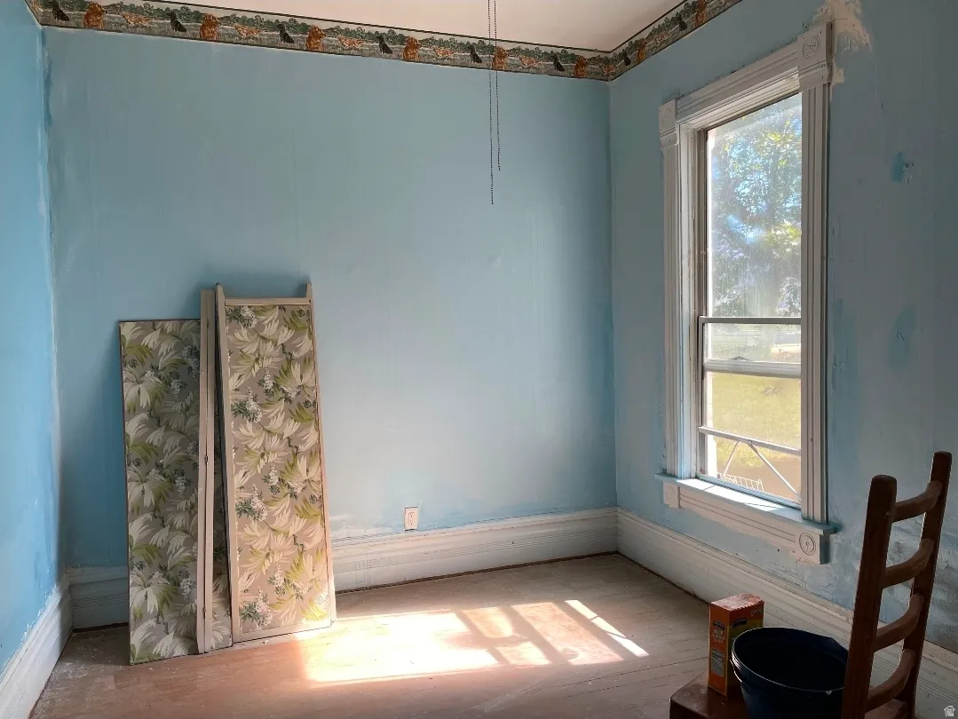 Room with light blue walls, white baseboards, and a single window featuring decorative white trim