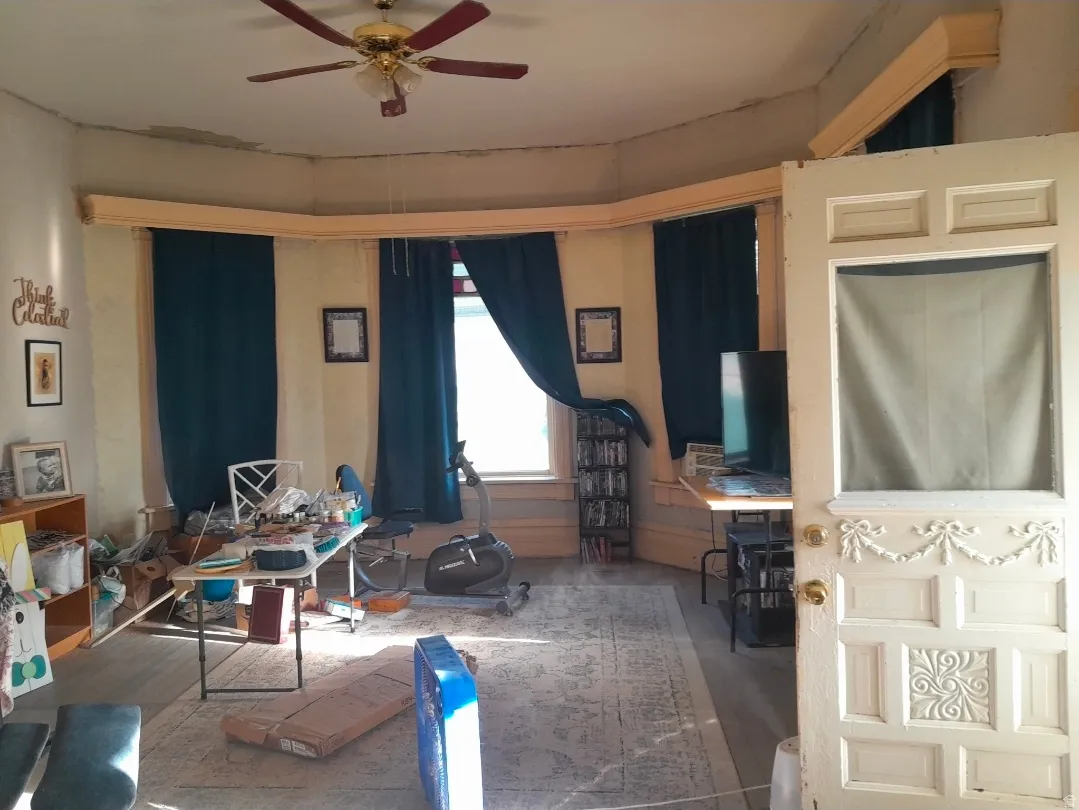 Spacious room featuring multiple windows, a ceiling fan, and decorative trim work