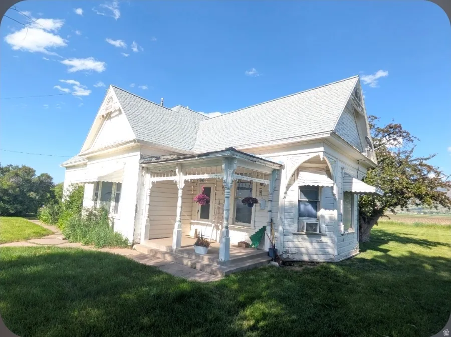 Victorian-style residence featuring a prominent front porch with decorative spindle work, a steeply pitched roof, and window awnings
