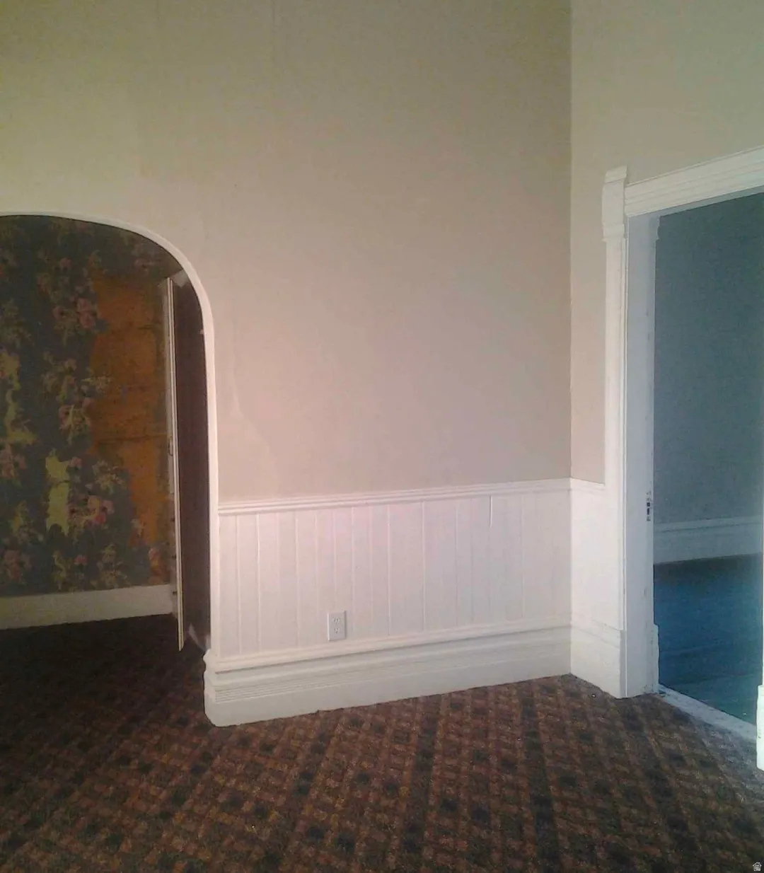 Room featuring white wainscoting, light-colored walls, and patterned carpet