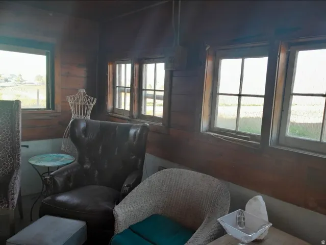 Room featuring wood-paneled walls, multiple windows providing natural light, and a visible exterior landscape