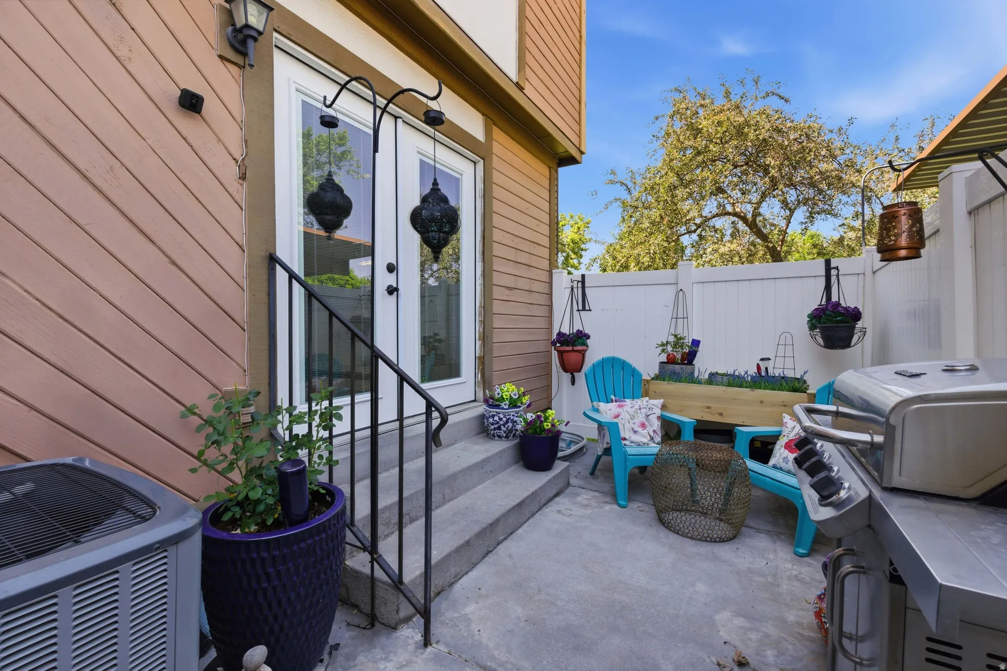 Outdoor patio featuring concrete surfacing, a privacy fence, and concrete steps leading to double glass-paneled doors with a black metal handrail