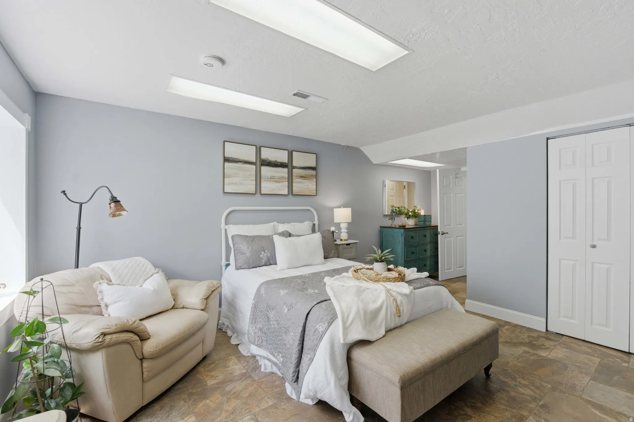 Spacious primary bedroom featuring neutral wall tones, recessed lighting, and durable tile flooring