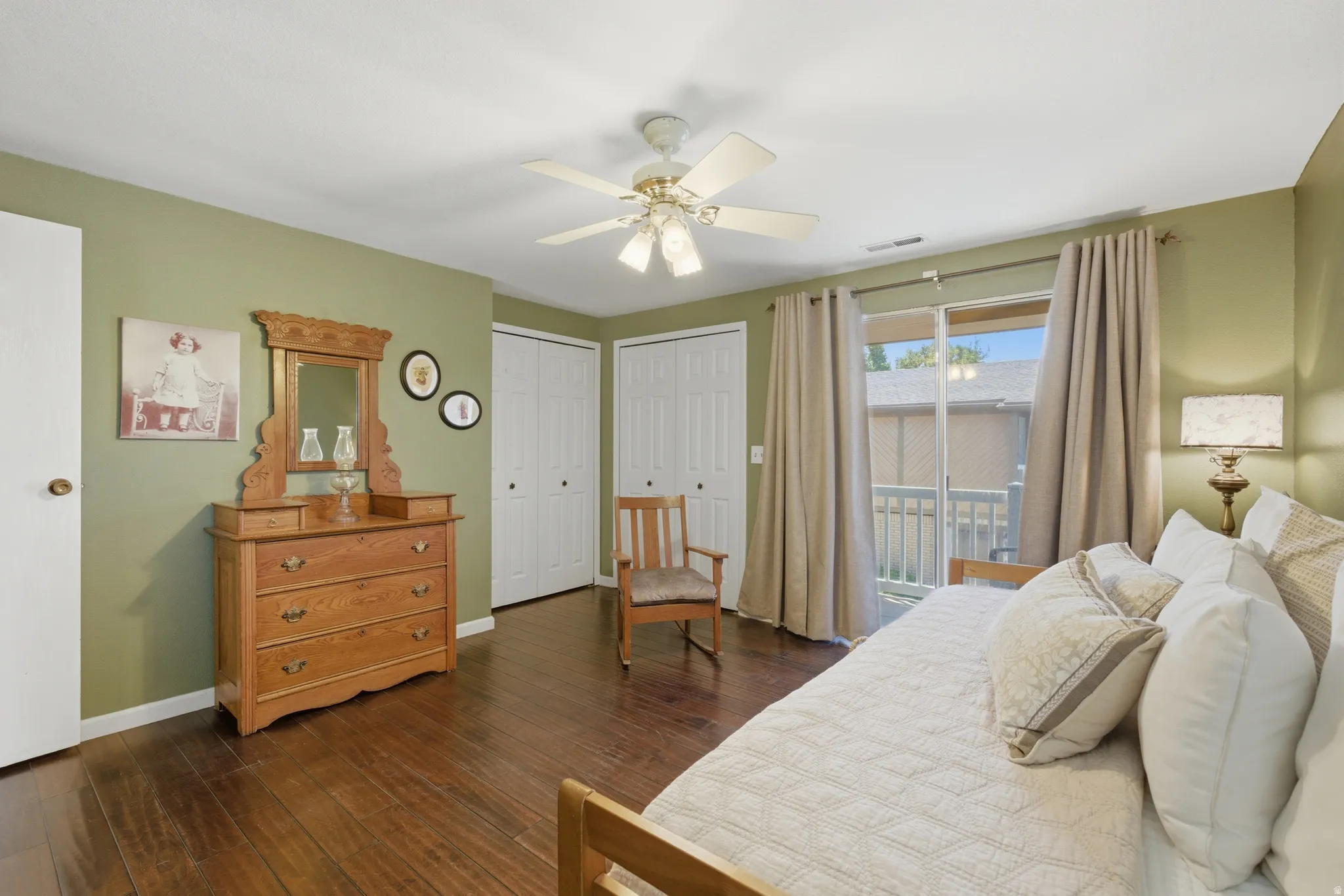 Spacious room featuring wood flooring, a ceiling fan, and two spacious closets