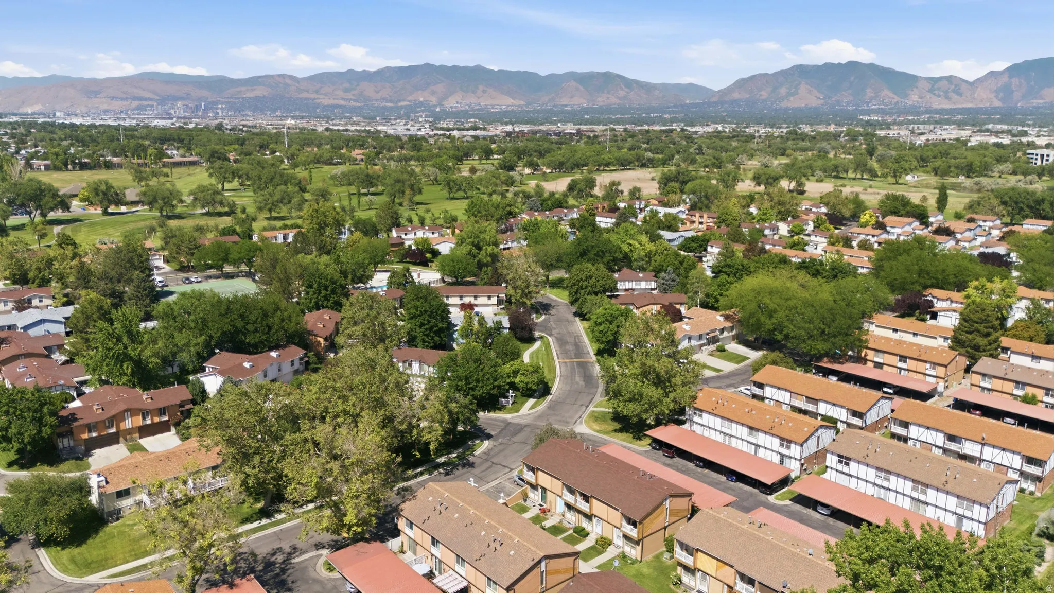 Expansive aerial showcasing a residential community with mature trees and mountain backdrops