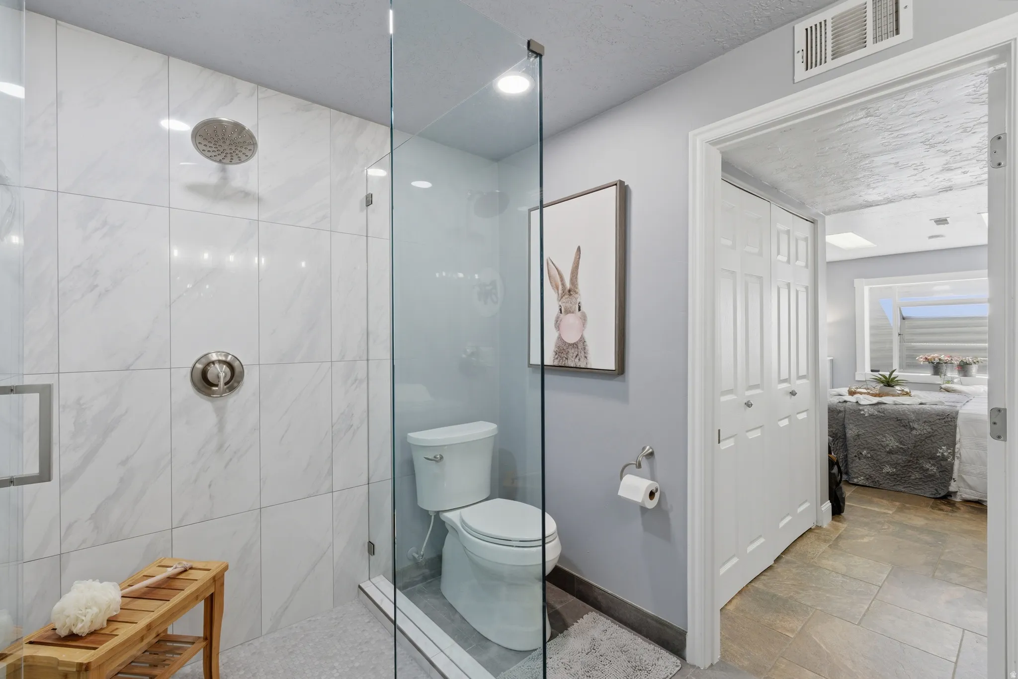 Glass-enclosed shower with white marble-look wall tiling, brushed nickel fixtures, and a rainfall showerhead
