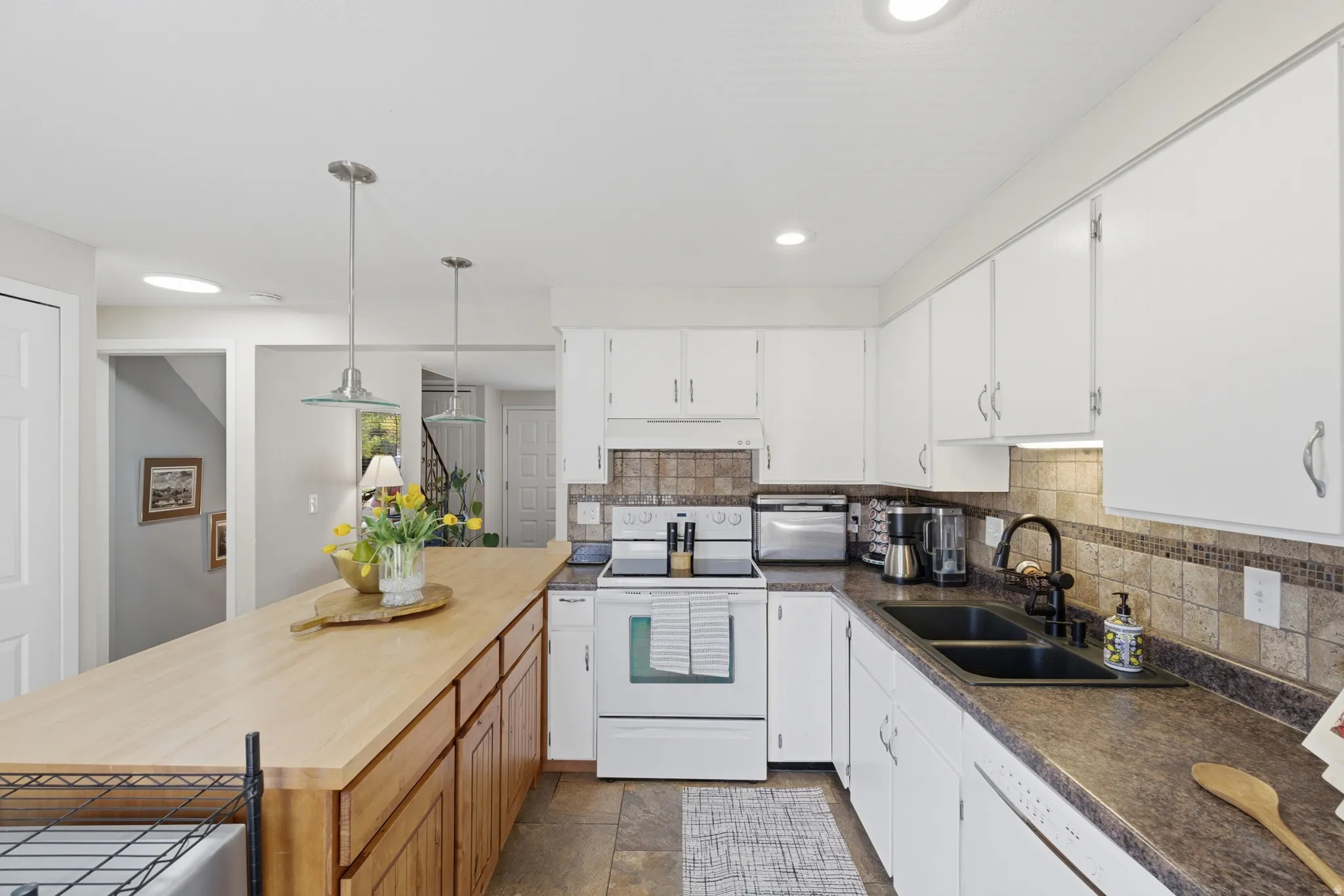 Kitchen featuring white cabinetry, a light wood-finish island countertop, and a dark stone-finish countertop