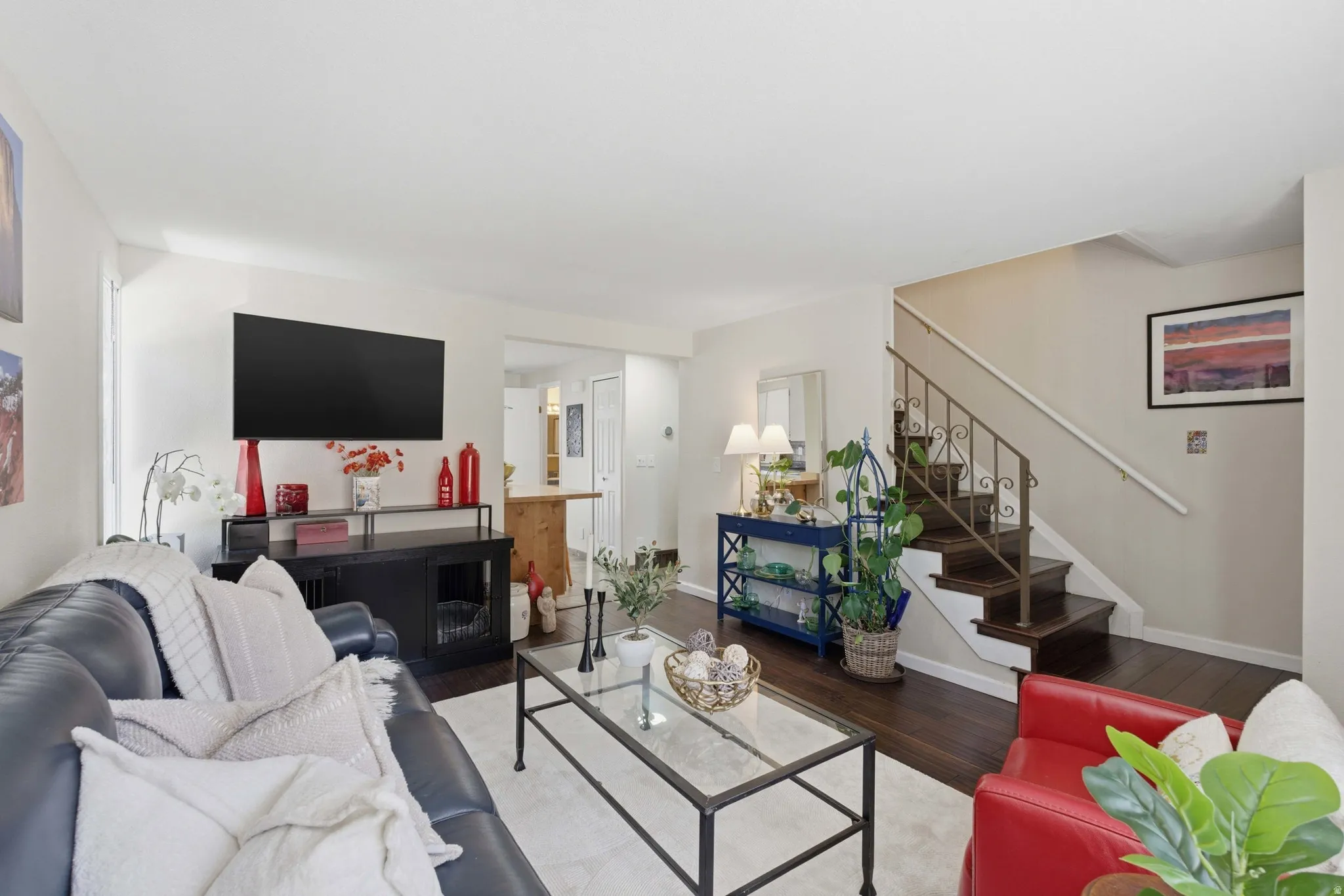 Living area featuring wood flooring, a staircase with decorative metal balusters, and light-toned wall finishes