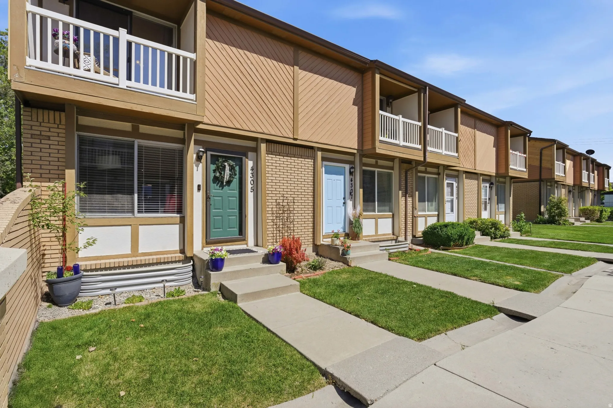 Exterior featuring tan siding, brick accents, and a second-story balcony with white railings
