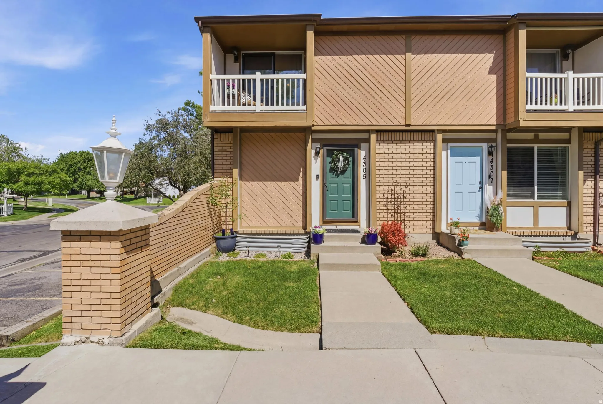 Townhome exterior featuring a private balcony, brick accents, and individual front entrances