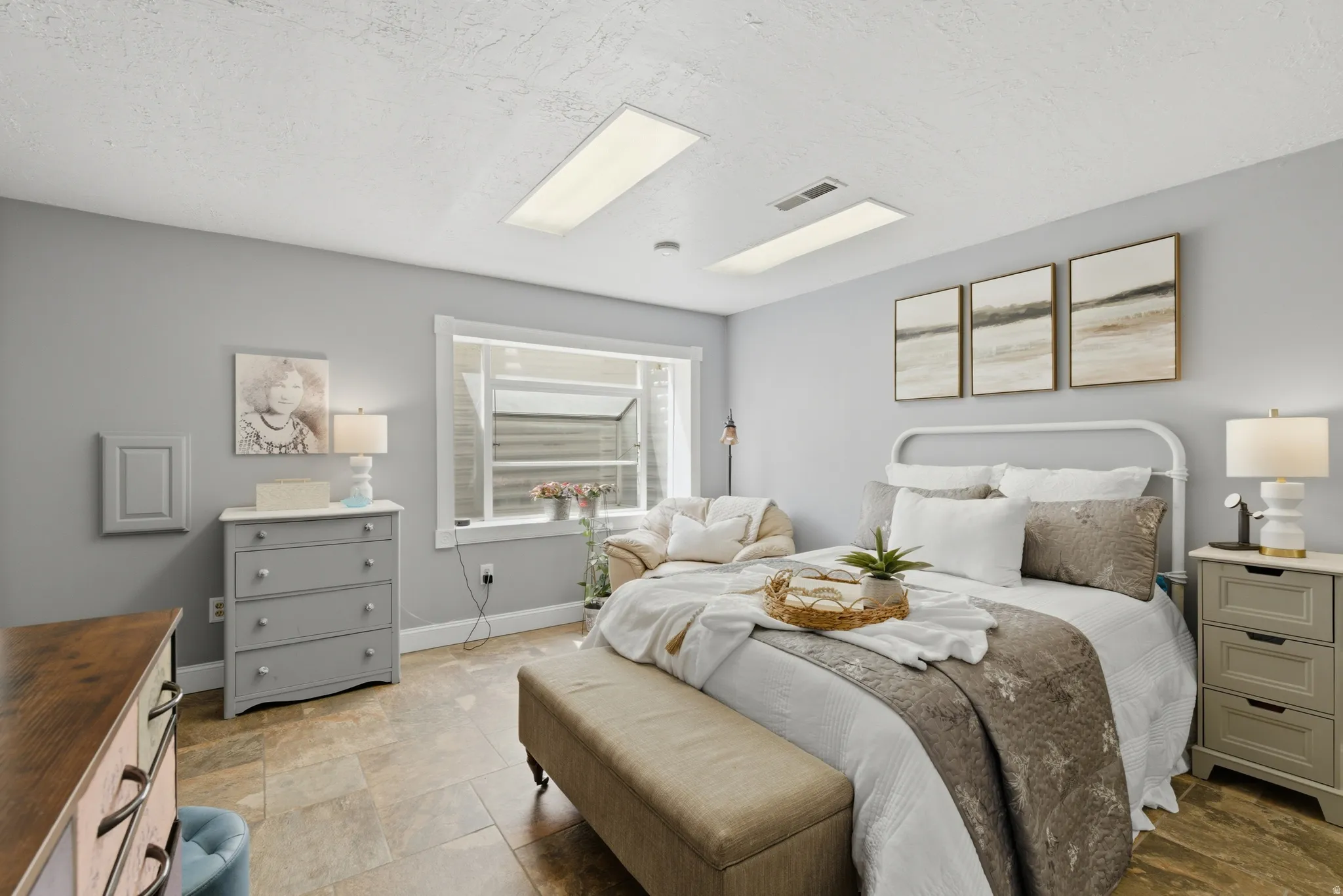 Spacious primary bedroom featuring neutral wall tones, recessed lighting, and durable tile flooring