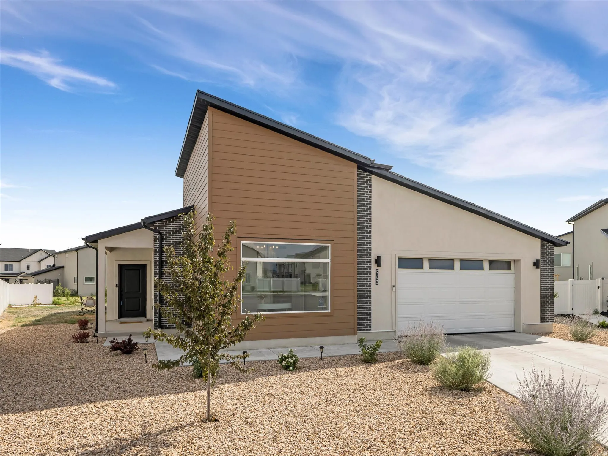 Contemporary exterior featuring mixed material siding, a white sectional garage door, and an angled roofline