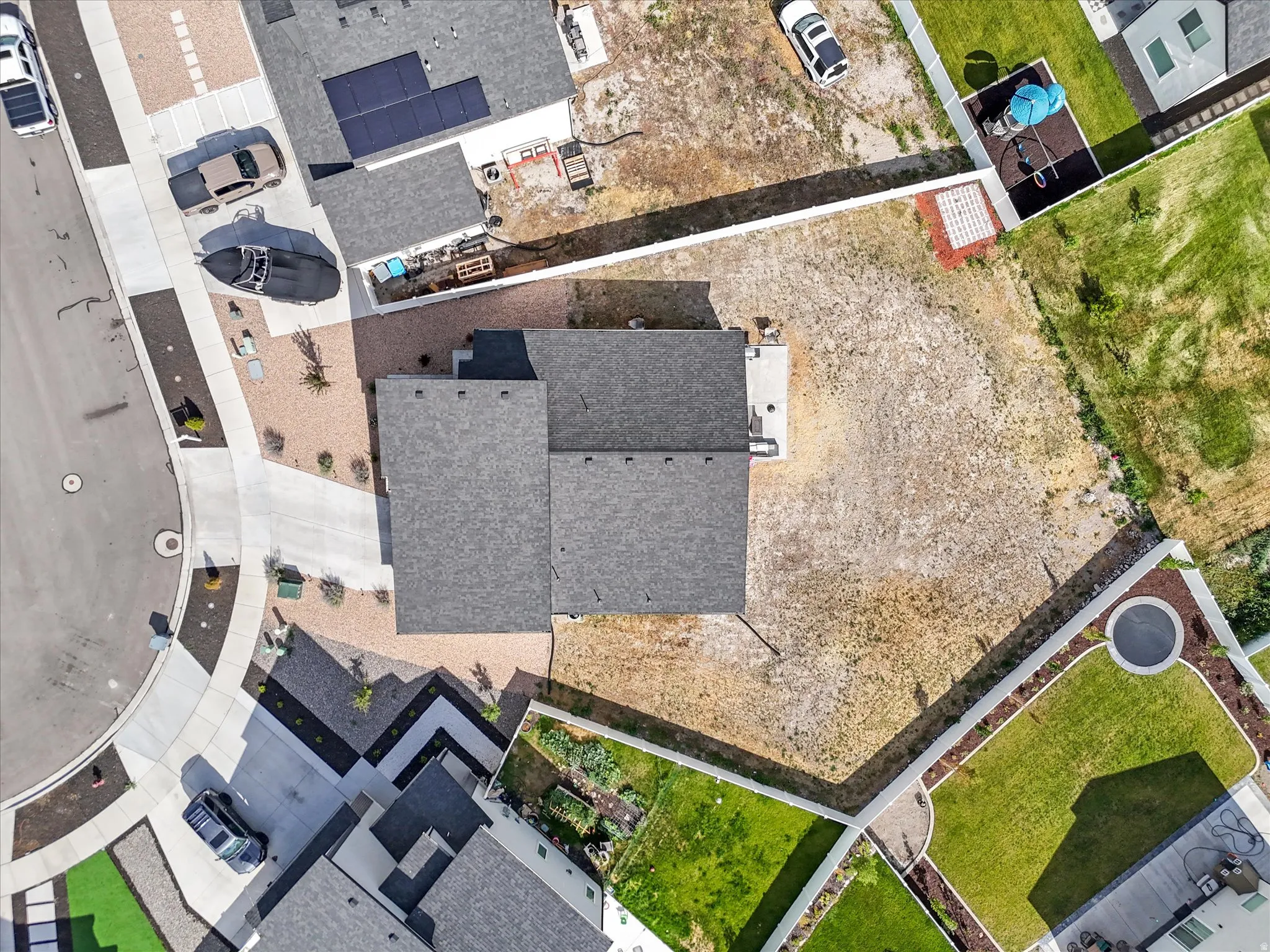 Overhead property view featuring a gray shingle roof, a concrete driveway, and an undeveloped rear yard