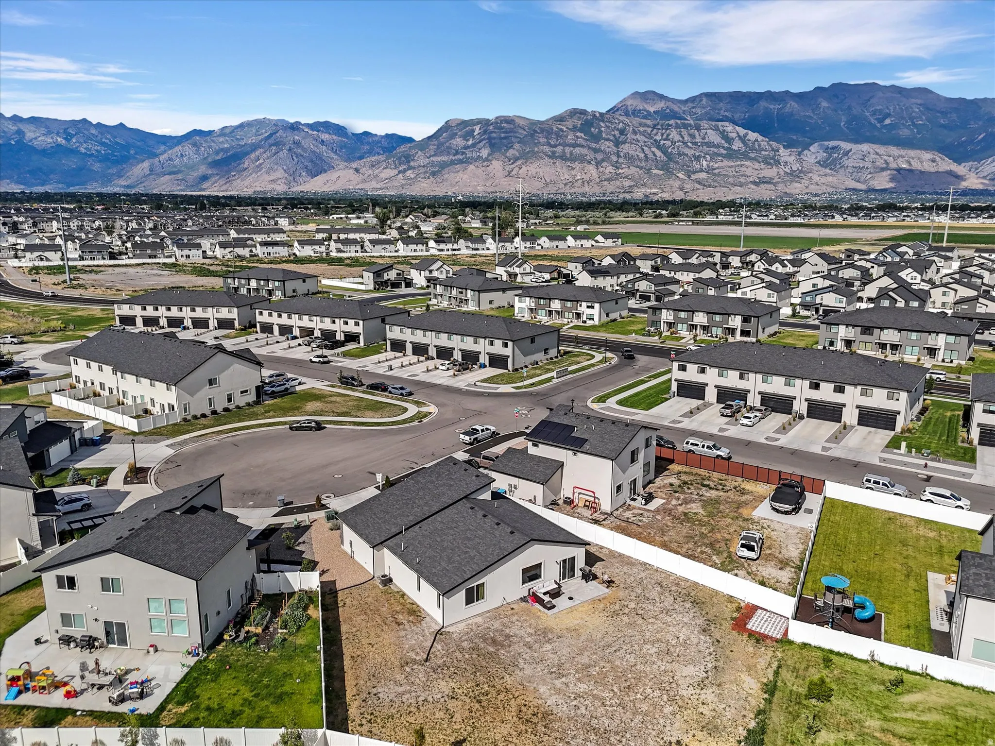 Modern residential development featuring a collection of detached homes and townhomes with dark gray roofs