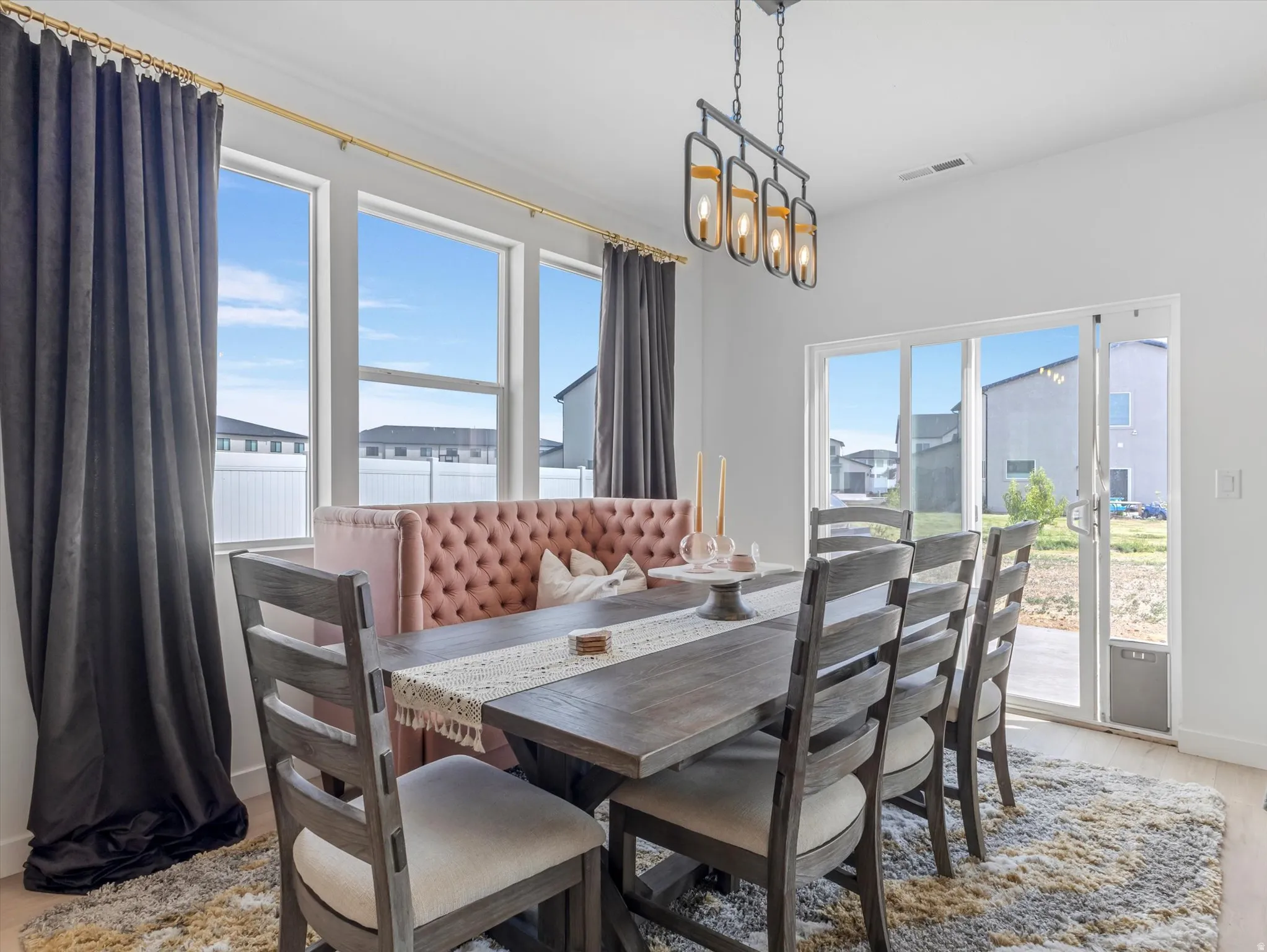 Dining area featuring a contemporary linear chandelier with four lights, multiple large windows, and a sliding glass door