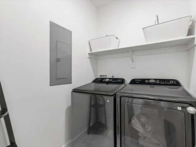 Dedicated laundry area featuring a white wall shelf, contemporary wall panel, and baseboard trim