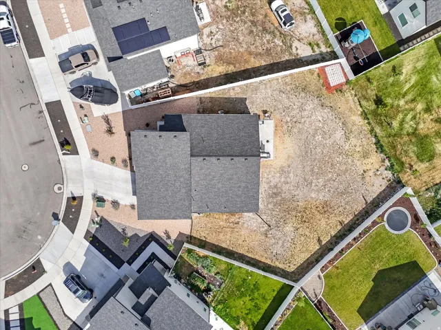Overhead property view featuring a gray shingle roof, a concrete driveway, and an undeveloped rear yard