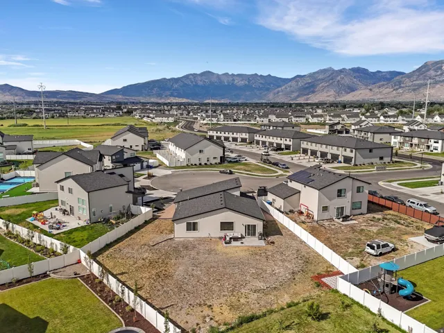 Expansive mountain range backdrop framing a residential community featuring single-family homes and townhomes with dark shingle roofs