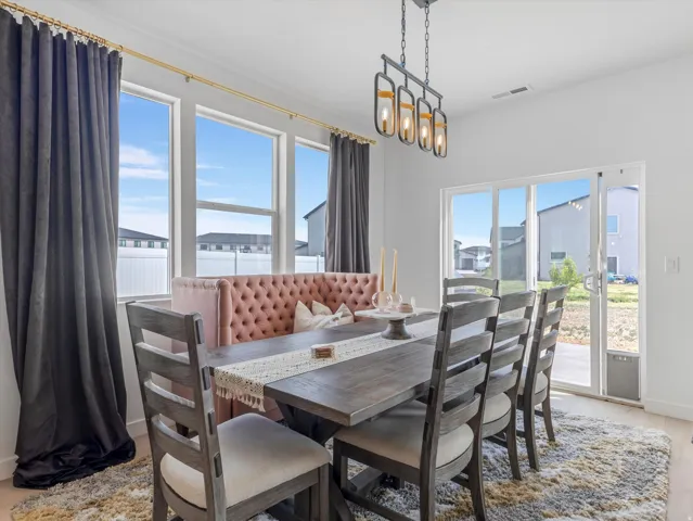 Dining area featuring a contemporary linear chandelier with four lights, multiple large windows, and a sliding glass door