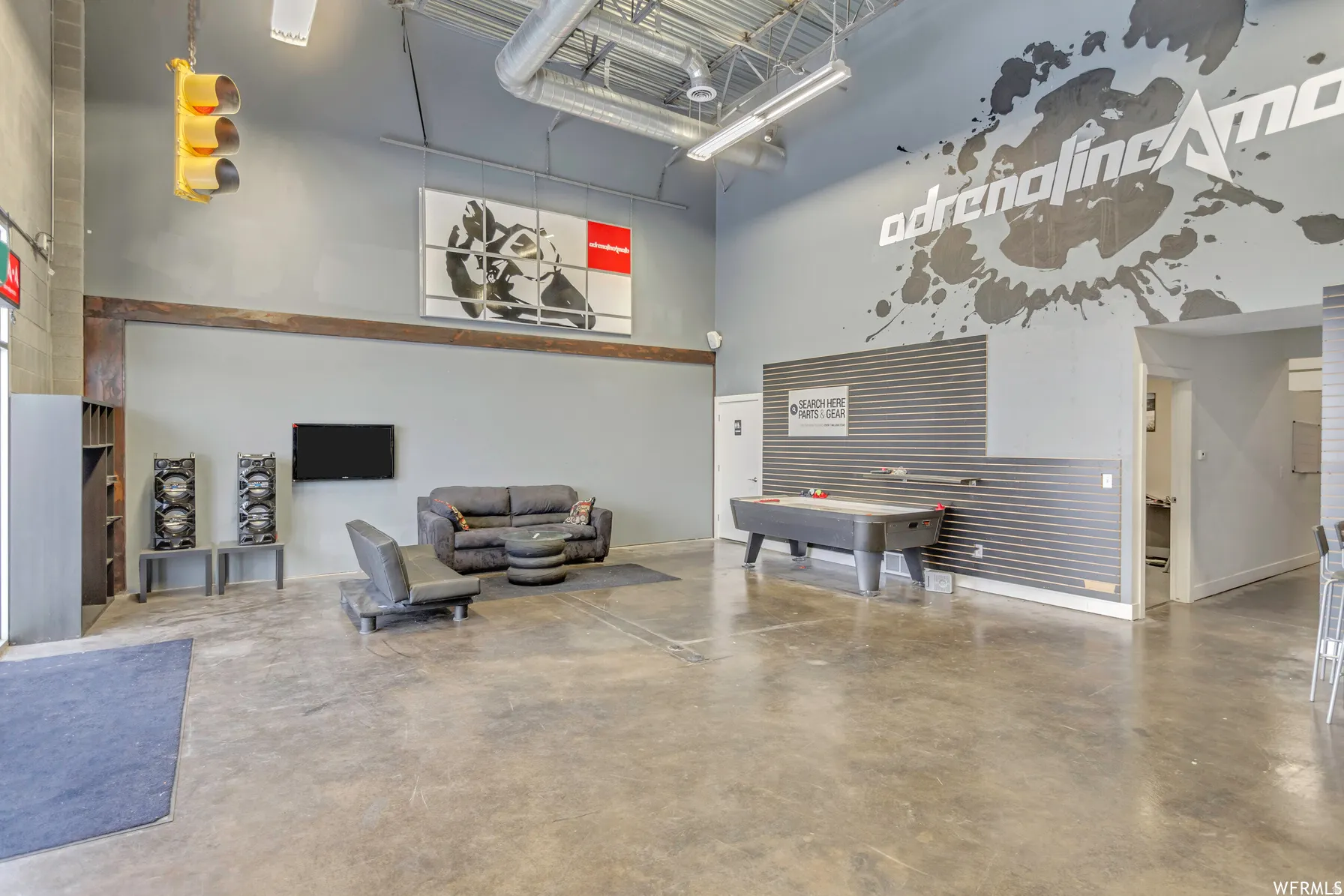 Spacious open-concept interior featuring high ceilings with exposed ductwork, polished concrete flooring, and a large accent wall with horizontal slat paneling